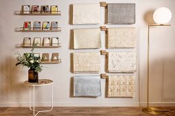 Side table below postcards on narrow shelves and sheets of wrapping paper hung from rods next to elegant standard lamp