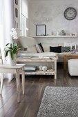 White orchid on wooden chair in front of narrow, hand-made console table next to sofa