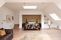 Patchwork bedspread on double bed in niche in open-plan bedroom area in converted attic