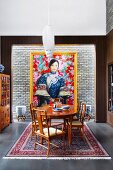 Fine wood dining table and chairs in front of gold frame picture with Asian woman motif on light brick wall
