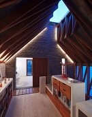 Glazed roof ridge, unusual roof structure and exposed brickwork with indirect lighting in gallery level of architect-designed house