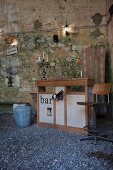 Sink unit on gravel floor and against rustic stone wall