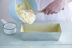 Gluten-free cake mixture being transferred to a loaf tin
