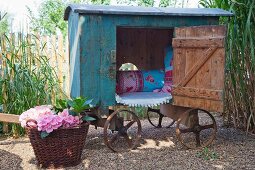 Vintage-style play house on cart and basket of flowering hydrangeas