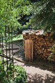 Brennholzstapel neben geschwungenem Kiesweg im Garten