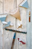 Selbstgebastelte Girlande mit Eistütenmotiv und Vögel an Holzwand aufgehängt