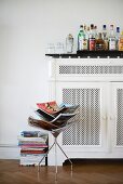 Bottles of various spirits on top of vintage-style radiator cover behind magazine rack