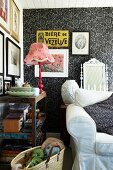 Pink table lamp on vintage wooden shelves and sofa against black and white patterned wallpaper