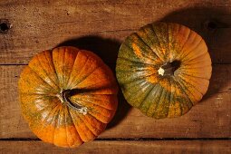 Two small pumpkins on a wooden surface