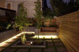 Illuminated, modern, terrace-house garden with wooden screens and view of neighbouring old building