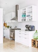 White country-style fitted kitchen with stainless steel gas hob and extractor hood