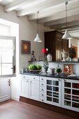 Küchenzeile mit weißen Unterschränken im Landhausstil und Thekenablage mit Pendelleuchten