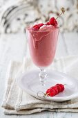 A raspberry shape with whipped cream and a raspberry skewer