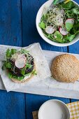 Vegetarischer Pilz-Hirse-Burger mit Rucola, Radieschen, frischen Sprossen und Joghurt-Meerrettich-Sauce