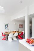 Red and white classic chairs around table in dining area in bright, open-plan interior