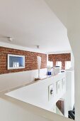 Gallery with exposed brick wall and standard lamp in office area at far end