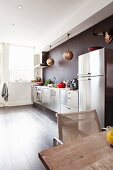 Stainless steel kitchen counter and fridge-freezer and Oriental-style pendant lamps against dark wall