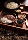 Various types of grains in wooden bowls in a rustic setting