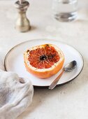 A baked caramelised grapefruit half on a plate