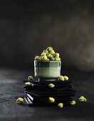Green Oriental snacks in a bowl on a stack of slate coasters