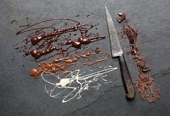 Geschmolzene Schokolade und geschnittene Schokolade auf grauem Untergrund