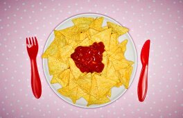 Tortillachips mit Salsa auf Teller mit Plastikbesteck (Aufsicht)