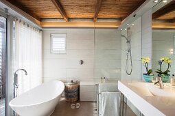Modernes Bad mit freistehender weißer Badewanne, Duschbereich und Schilfrohrdecke