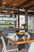 Moderne Einbauküche mit Küchentheke, Esstisch unter Schilfrohrdecke mit Holzbalkenkonstruktion