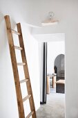 Old wooden ladder leaning against white wall for use as a clothes rack in bedroom