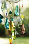 Glittering crystal pendants and beads hanging from hand-crafted wind chimes in garden