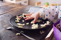 Kinderhand greift nach Hörnchennudeln