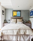 Double bed with headboard below framed sports strips flanked by collection of trophies on bedside tables in elegant bedroom