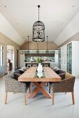 Leopard-print armchairs at long wooden table below pendant lamp with bird-cage lampshade in open-plan interior