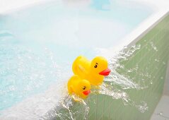 Water slopping out of bath carrying rubber duckies