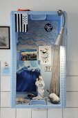 Arrangement of beach finds and souvenirs in old herring crate on wall