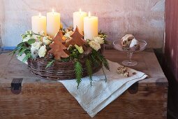 A woven basket with advent candles, Japanese roses, coral roses and conifer sprigs