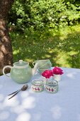 Tealight holders with crocheted covers and vintage coffee service on garden in dappled shade