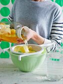A woman sieving iced tea with lemon peel