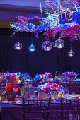 Festlich dekorierter Tisch mit Blumengesteck, oberhalb schwebender Zweig mit Glaskugeln - für eine indische Hochzeit