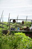 Töpferware und Gartenwerkzeug auf Vintage Holzgestell vor Gartenzaun