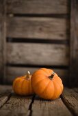 Two small pumpkins on a wooden surface