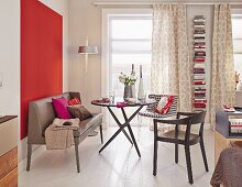 Leder Sitzbank und verschiedene Stühle um rundem Tisch vor rot gestrichener Wand im Ein-Zimmer-Appartement