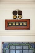 Vintage room-service bells with room display panel above blue and green stained glass interior door