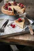 Vegan cheesecake with raspberries on a metal tray on wooden surface