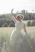 A young bride waving in an oat field