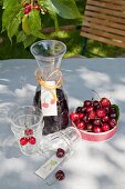 Carafe with hand-made label, glasses and dish of cherries