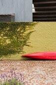Red canoe leant against yellow brick courtyard wall