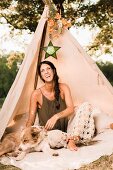 Laughing woman and dog sitting in decorated teepee