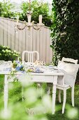 Kronleuchter über romantischem Kaffeetisch im Garten mit blauer Blumendeko