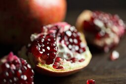 Whole and broken pomegranates on a dark surface